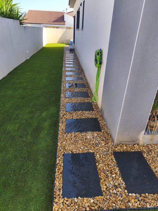 Gazon synthétique, gravier et dalles d’ardoise dans un jardin à Pia