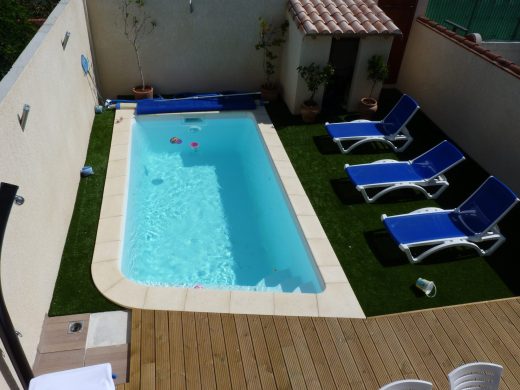 Piscine bordée de gazon synthétique et de transats