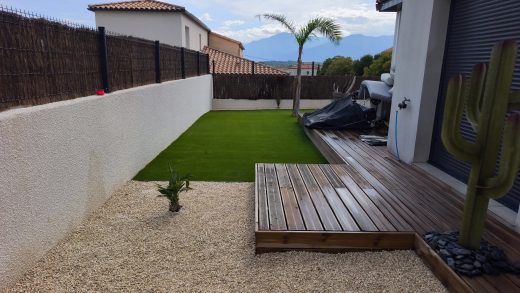 Gazon synthétique et terrasse en bois dans un jardin