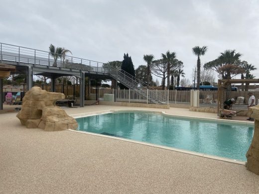 Plage de piscine en moquette de pierre au camping Les Tamaris