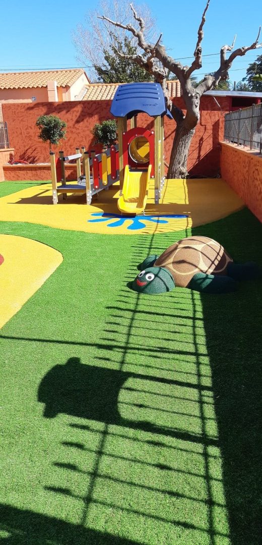 Structure de jeux avec toboggan sur un sol amortissant coulé et du gazon synthétique